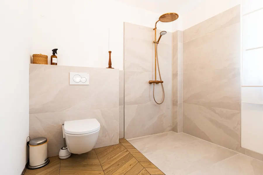 Bodengleiche Dusche ohne Schwelle, Wand-WC und Holzoptikboden in einem Bad von Linnemeier