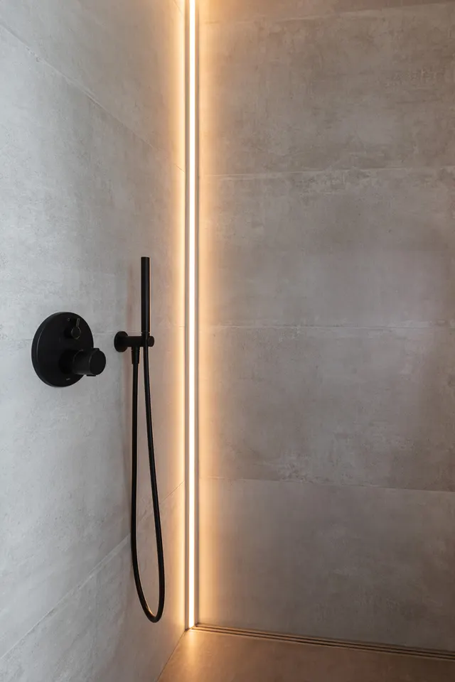Dusche mit senkrechter LED-Lichtleiste und schwarzer Armatur, gebaut von Linnemeier