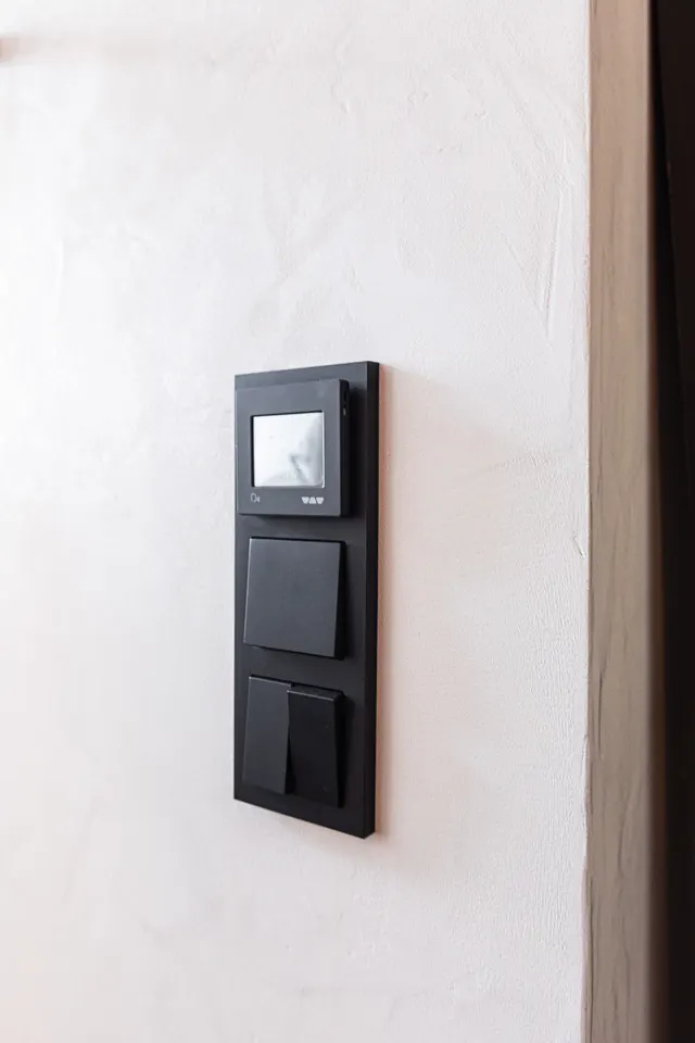 Schwarzer Lichtschalter auf einer verputzten Wand im Detail