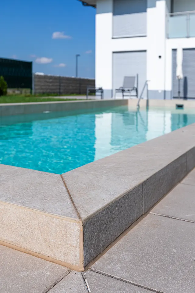 Natursteinplatten am Poolrand mit Blick aufs Haus